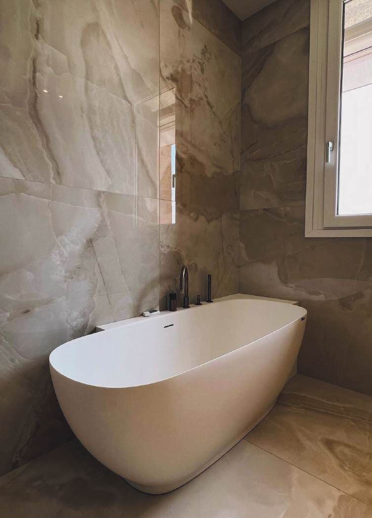 Bagno con vasca freestanding e rivestimento effetto marmo