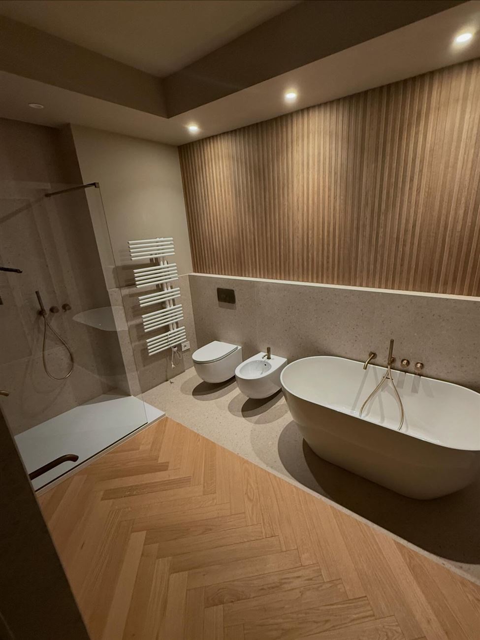 Bagno ristrutturato con vasca freestanding, parquet a spina di pesce e boiserie in legno